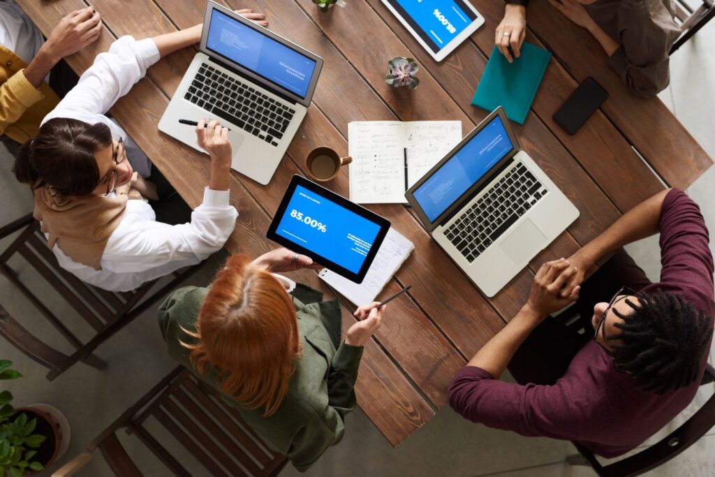 Coworkers collaborating around laptops at a shared desk